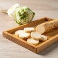 Sliced Ginseng Root Displayed on a Wooden Tray with Fresh Herbs in Beige Setting Royalty Free Stock Photo