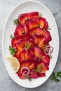 Sliced Gravlax,  scandinavian beet cured salmon  served with red onion, capers and lemon on white plate Royalty Free Stock Photo