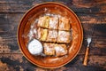 Sliced Greek Bougatsa pie with phyllo dough and semolina custard cream. Dark Wooden background. Top view