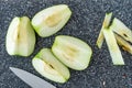 Sliced green Granny Smith apple on a plastic man made faux gray granite cutting board, chefs knife, apple quarters Royalty Free Stock Photo