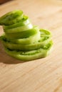 Sliced green tomatoes are stacked on a wooden cutting board. Royalty Free Stock Photo