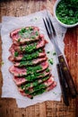 Sliced grilled barbecue beef steak with green chimichurri sauce Royalty Free Stock Photo