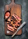 Sliced grilled Beef steak with knife and fork for meat on wooden cutting board
