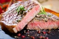 Sliced grilled meat barbecue steak Striploin with knife and fork carving set on black stone slate. Royalty Free Stock Photo