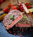 Sliced grilled meat barbecue steak Striploin with knife and fork carving set on black stone slate. Royalty Free Stock Photo