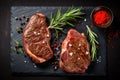 Sliced grilled meat steak with spices rosemary and pepper on black marble board