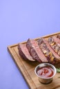 Sliced grilled Medium rare barbecue Steak on bone with spices served on a rustic wooden board over blue background. Royalty Free Stock Photo