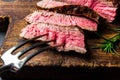 Sliced grilled medium rare beef steak served on wooden board Barbecue, bbq meat beef tenderloin. Top view, slate