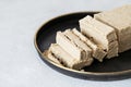 Sliced halva in a black plate on a white background. Sunflower halva close-up. Oriental dessert