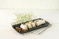 Sliced halva with nuts and dried fruits on a plate served with flowers and fruits on white table