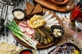 Sliced ham, bacon, lard, pickles, green onions, slices of rye bread on cutting board over rustic background. Appetizer for vodka, Royalty Free Stock Photo