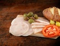 Sliced ham salami decorated on wooden board with olives, tomato Royalty Free Stock Photo