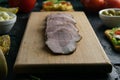 Sliced ham on a wooden board, around the ham, green onions, tomato, souce, olives, lemon, spice, dill and parsley Royalty Free Stock Photo