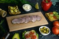 Sliced ham on a wooden board, around the ham, green onions, tomato, souce, olives, lemon, spice, dill and parsley Royalty Free Stock Photo