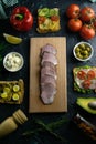 Sliced ham on a wooden board, around the ham, green onions, tomato, souce, olives, lemon, spice, dill and parsley Royalty Free Stock Photo