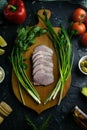 Sliced ham on a wooden board, around the ham, green onions, tomato, souce, olives, lemon, spice, dill and parsley Royalty Free Stock Photo