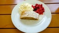 Sliced homemade berry strudel served with fresh red currants and powdered sugar on a plate with whipped cream.