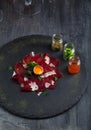 Sliced homemade cured beef with egg and spices on the stone taable, dark photo Royalty Free Stock Photo