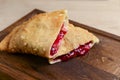 Sliced homemade strudel pie with cherry filling close-up on a dark wooden cutting board horizontal. Royalty Free Stock Photo