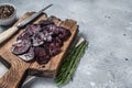 Sliced Horse dried sausage on woooden board with herbs. Gray background. Top view. Copy space