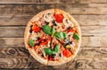 Sliced italian pizza with salami, mozzarella, mushroom, tomatoes, black olives and basil leaves on black background. Italian Royalty Free Stock Photo