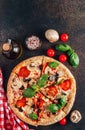 Sliced italian pizza with salami, mozzarella, mushroom, tomatoes, black olives and basil leaves on black background. Italian Royalty Free Stock Photo