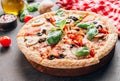 Sliced italian pizza with salami, mozzarella, mushroom, tomatoes, black olives and basil leaves on black background. Italian Royalty Free Stock Photo