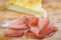 Sliced italian smoked speck ham with focaccia bread on a wooden cutting board Royalty Free Stock Photo