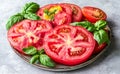 Sliced juicy red tomatoes are presented on a plate with basil leaves Royalty Free Stock Photo