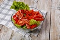 Sliced juicy ripe summer tomatoes and crisp lettuce leaves in a glass bowl on a light rustic background. Olive oil and spices Royalty Free Stock Photo