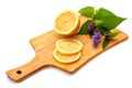 Sliced lemon and branch of flowering mint on wooden board over white background.
