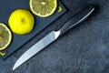 Sliced lemon on a cutting plastic board and a silver knife on a marble table background. Close-up.