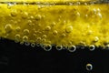 A sliced lemon`s detail in a glass of soda with bubbles, black background, close up