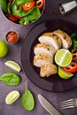 Sliced lime pork tenderloin and fresh healthy spinach salad on dark background top view Royalty Free Stock Photo