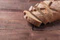 Sliced loaf of dark homemade bread dusted with flour is lying on brown boards