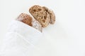 Sliced loaf of homemade bread in a paper on a white background w