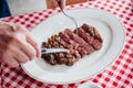 Sliced medium rare charcoal grilled wagyu Ribeye steak in white plate on red and white pattern tablecloth