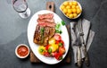 Sliced medium rare grilled beef steak served on white plate with tomato salad and potatoes balls. Barbecue, bbq meat Royalty Free Stock Photo