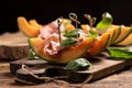 Sliced melon with ham and basil leaves, served on a wood chopping board Royalty Free Stock Photo