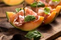 Sliced melon with ham and basil leaves, served on a wood chopping board Royalty Free Stock Photo