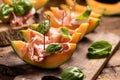 Sliced melon with ham and basil leaves, served on a wood chopping board Royalty Free Stock Photo