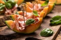 Sliced melon with ham and basil leaves, served on a wood chopping board Royalty Free Stock Photo