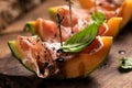 Sliced melon with ham and basil leaves, served on a wood chopping board Royalty Free Stock Photo