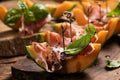 Sliced melon with ham and basil leaves, served on a wood chopping board Royalty Free Stock Photo