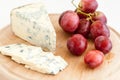 Tasty sliced moldy cheese and red grapes on wooden plate Royalty Free Stock Photo