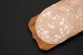 Sliced Mortadella Bologna Meat on a rustic wooden board over black background, top view. Flat lay, from above, overhead. Space for