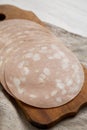 Sliced Mortadella Bologna Meat on a rustic wooden board, side view. Closeup