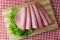 Sliced mortadella on cutting board in kitchen with rustic table