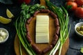 Sliced mozzarella on a wooden board, around the ham, green onions, tomato, souce, olives, lemon, spice, dill Royalty Free Stock Photo