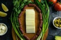 Sliced mozzarella on a wooden board, around the ham, green onions, tomato, souce, olives, lemon, spice, dill Royalty Free Stock Photo